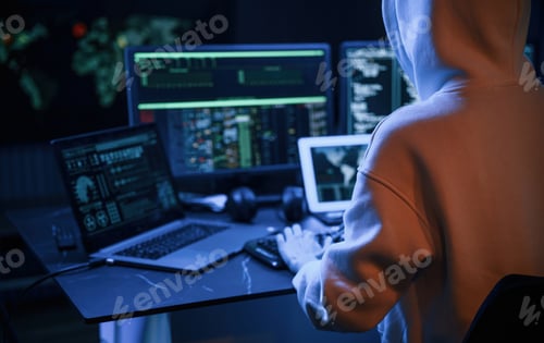 Preview: Young professional female hacker is indoors by computer with lot of information on displays
