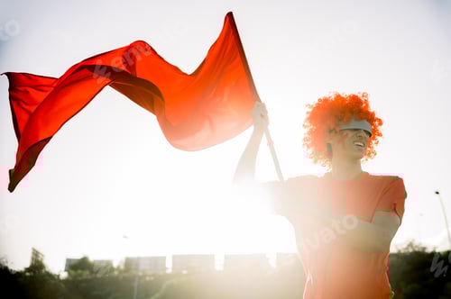 Preview: Young ethnic man in VR glasses waving flag on street