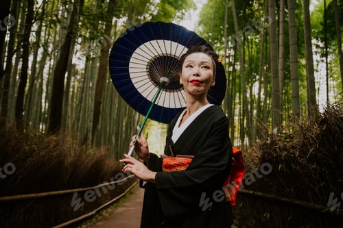 Preview: Beautiful japanese senior woman walking in the bamboo forest