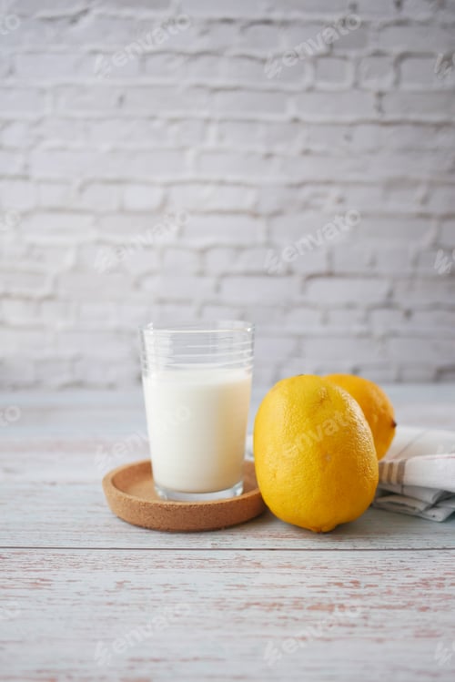 Preview: Yellow Lemon and glass of milk on table