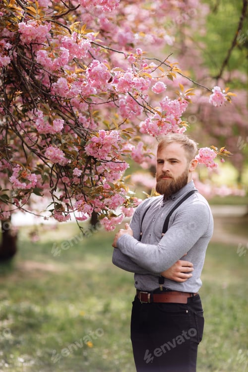 Preview: Hipster near blossoming of sakura. Harmony with nature concept. Man with beard and mustache near