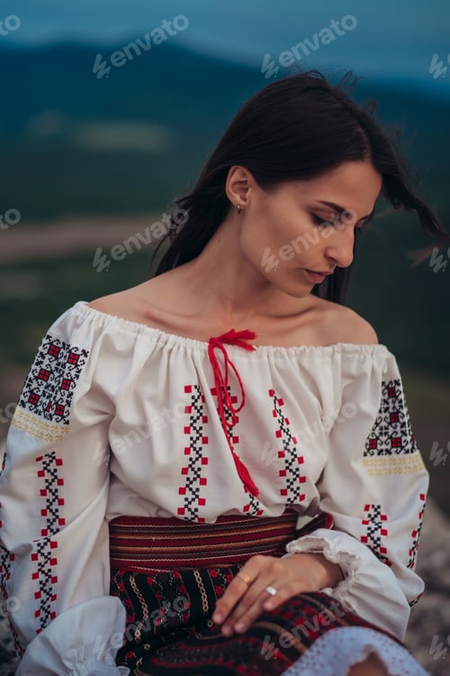 Preview: Atractive woman in traditional romanian costume on mountain green blurred background