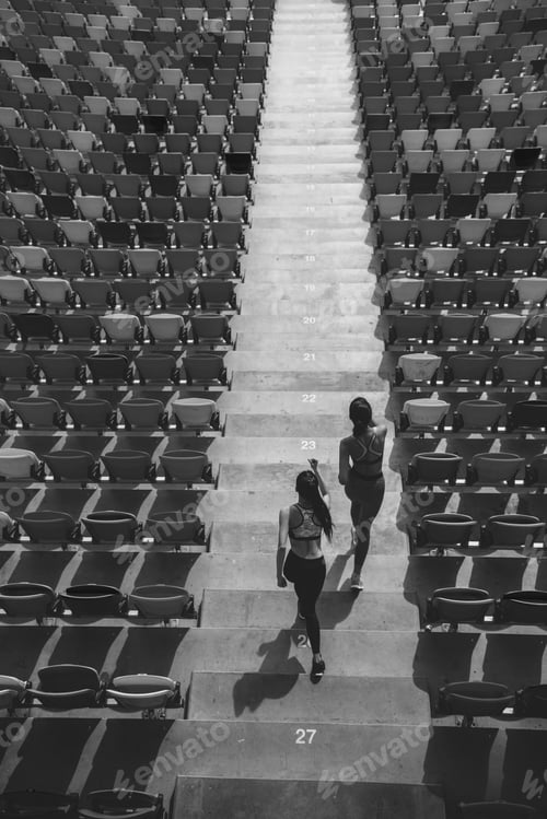 Preview: two sportswomen running on stadium stairs, black and white, running women concept