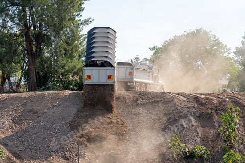 Preview: A large construction truck pouring dirt into a hole