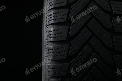 Preview: Winter tire on black background, closeup. Car maintenance