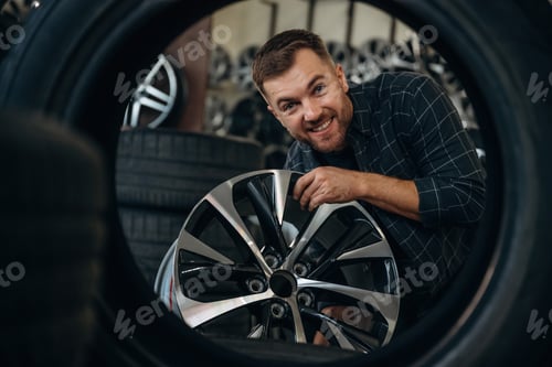 Preview: Looking through the hole in tire. Man worker is maintenance station with wheels