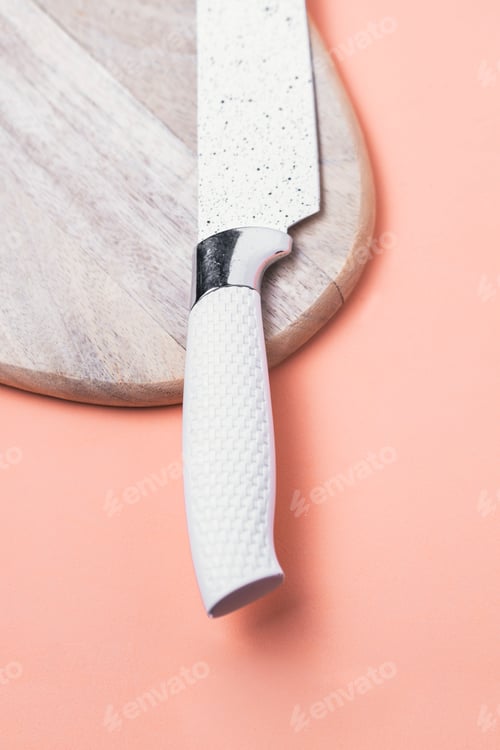 Preview: Cooking concept. Cutting board with a white kitchen knife on a pink background.