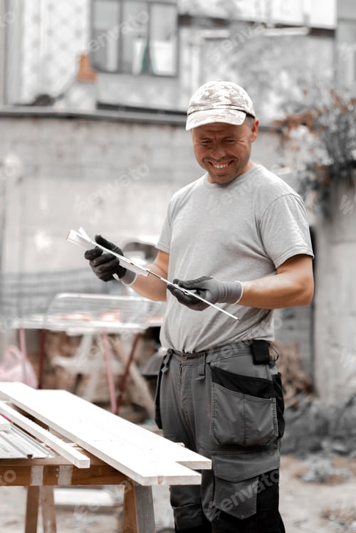 Preview: Young builder with a construction measuring tape in his hands.