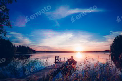 Preview: Sunset on a lake. Wooden pier with fishing boat at sunset in Finland