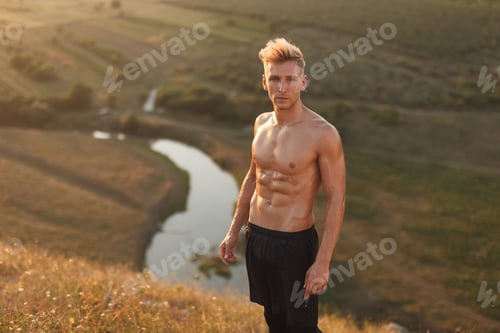 Preview: Muscular sportsman standing in countryside