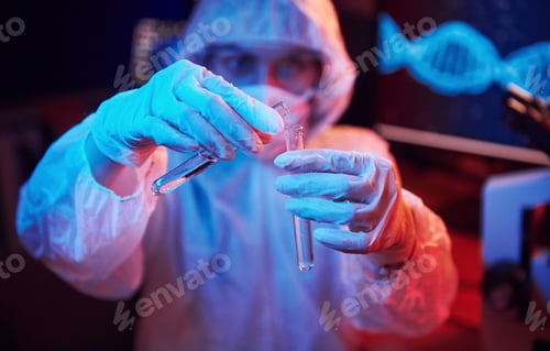 Preview: Nurse in mask and white uniform, holding tube with liquid and sitting in neon lighted laboratory