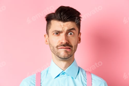 Vista previa: Close-up of anxious young guy with moustache, biting lip and frowning, looking worried over small