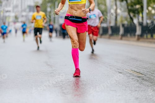 Preview: legs female runner in pink compression socks run in rain on wet road marathon