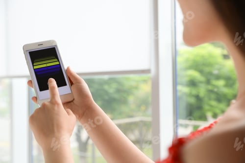 Preview: Woman using smart home application on phone to control window blinds indoors, closeup