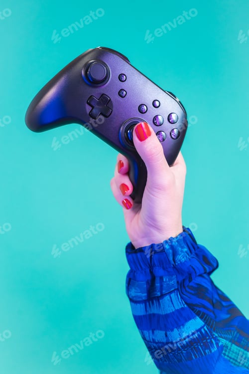 Preview: Female hand holding a video game controller gamepad isolated on a blue background studio.