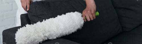 Preview: cropped view of housewife cleaning couch with dust brush, banner