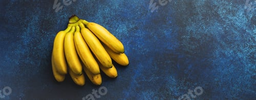 Preview: Branch of fresh baby bananas on dark blue concrete background. Natural tropical fruit. Top view