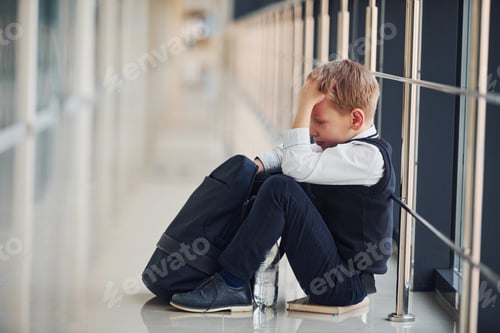Preview: Boy in uniform sitting alone with feeling sad at school. Conception of harassment