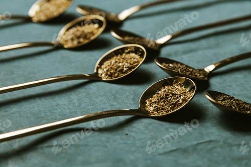 Preview: A group of golden spoons with tea over a blue background