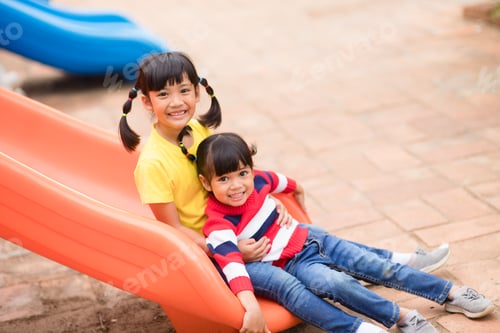 Preview: Cute little girls siblings having fun on playground outdoors on sunny summer day.