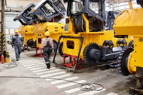 Preview: Blurry figures of contemporary engineers of factory moving along row of machines