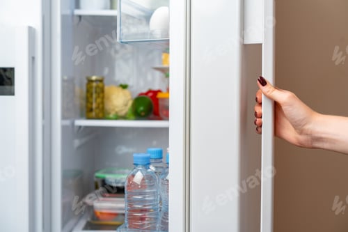 Preview: Female hand opens door of a fridge