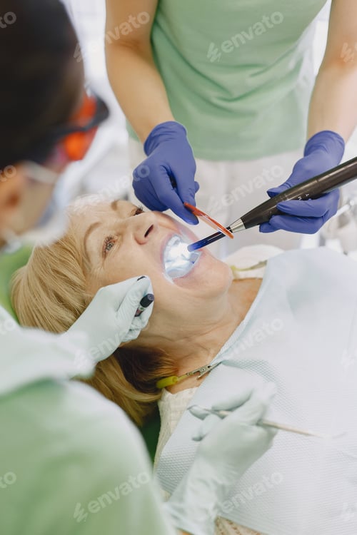 Preview: Dentist looking her old patient with tools