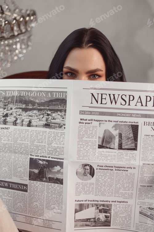 Preview: Young brunette woman in home clothes reads newspaper with her legs on table. Weekend concept