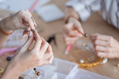 Preview: cropped shot of women making accessories of beads at workshop