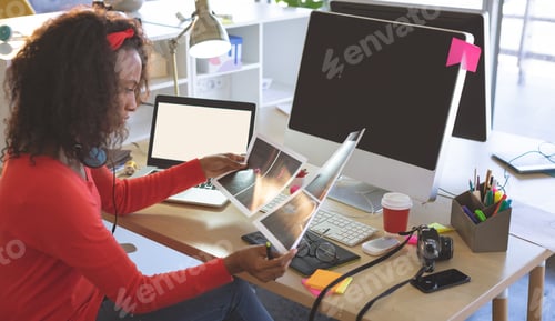 Preview: Creative professional reviewing design prints at modern office desk with technology, copy space