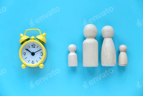 Preview: Quality time spent with family. Alarm clock with wooden people represent a parent and children.