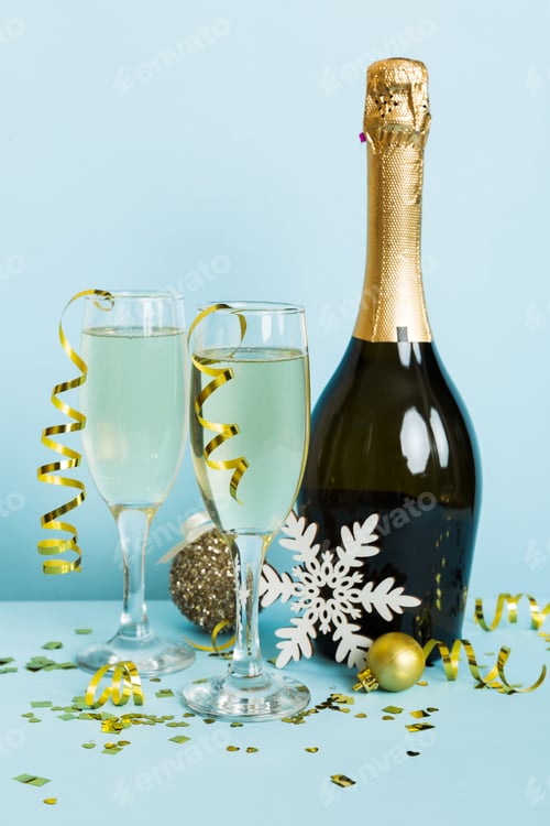 Preview: Champagne bottle with confetti, glasses and christmas decor on colored holiday