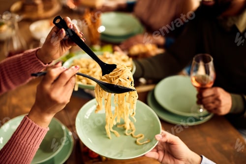 Preview: Close-up of people having pasta for lunch at dining table.