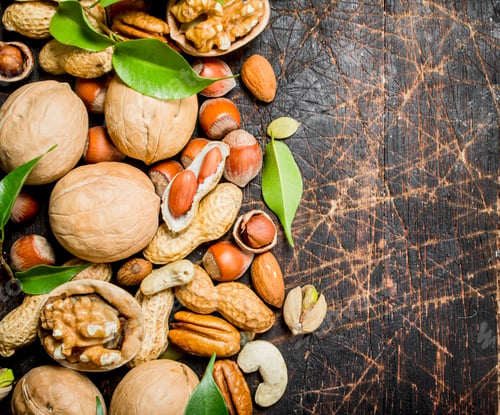 Preview: Nuts background. Different kind of nuts with green leaves.