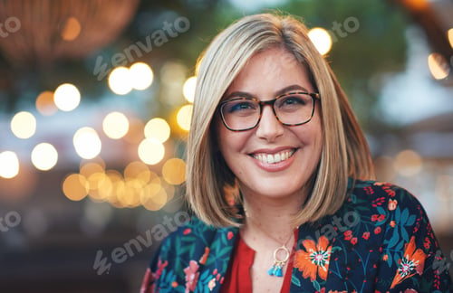 Preview: Portrait beautiful blonde woman smiling happy in city evening with lights in background