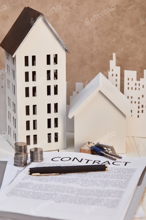 Preview: houses models on white wooden table with contract, keys and coins, real estate concept