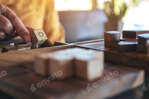 Preview: Closeup image of people playing wooden Tic Tac Toe game or OX game