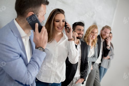 Preview: Young people with mobile phones standing by the grey wall