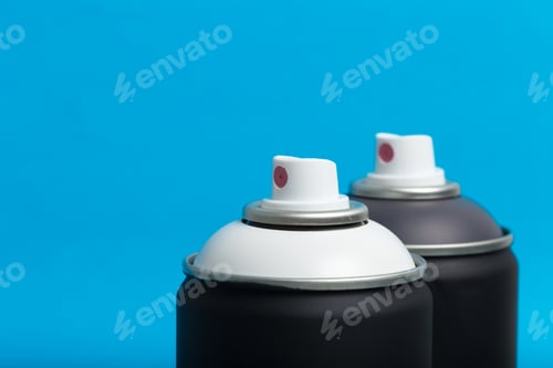 Preview: Close-up of spray paint cans with white and black tops against a bright blue background