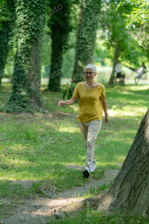 Preview: Senior woman enjoying a leisurely walk in the park for health and relaxation.