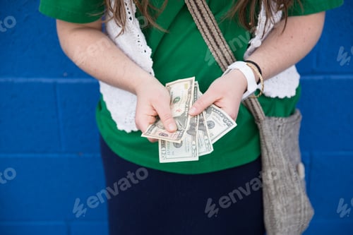 Preview: A woman counting several $20 bills