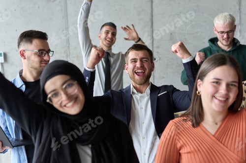Preview: A diverse team of business professionals ecstatically celebrating their success in a modern office
