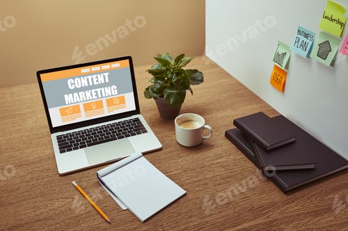 Preview: laptop with"content marketing" lettering on screen, notebooks and pencil on wooden tabletop,