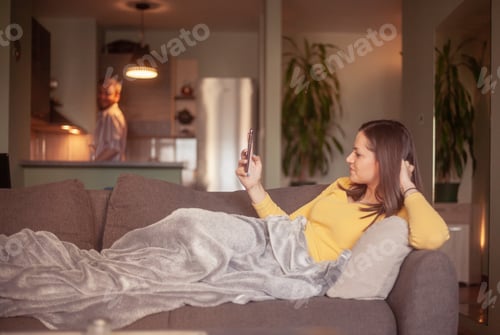 Preview: Two People, In Living Room, Doing House Choirs. Woman Relaxing While Man Is In Kitchen In