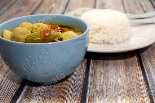 Preview: Green Curry With Fish Balls And Steamed Rice On A Wooden Table
