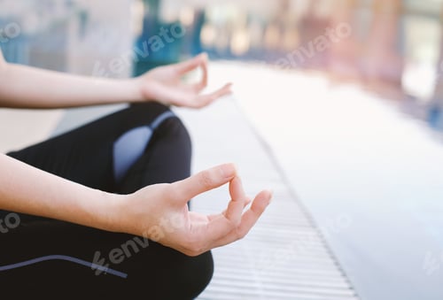 Preview: Woman meditating in the lotus position closeup at outdoor swimming pool with copy space
