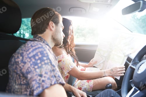 Preview: Couple sitting in car looking at folding map