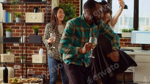 Preview: Multiethnic colleagues doing energetic dance moves and laughing in cozy living room