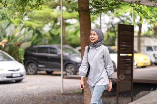 Preview: Asian Indonesian Muslim woman walking outdoors with handbag
