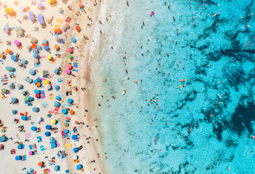 Preview: Aerial view of sandy beach with umbrellas and sea at sunset